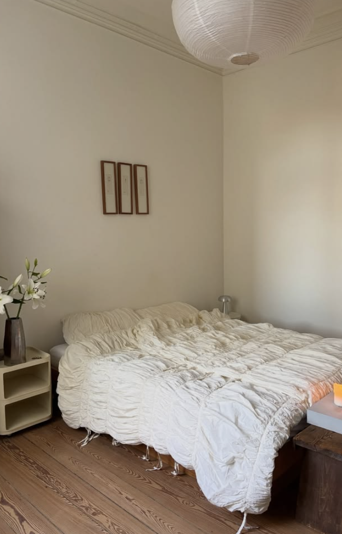 Bedroom with a ruffled white bed and pendant light